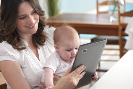 Mother using digital tablet with baby