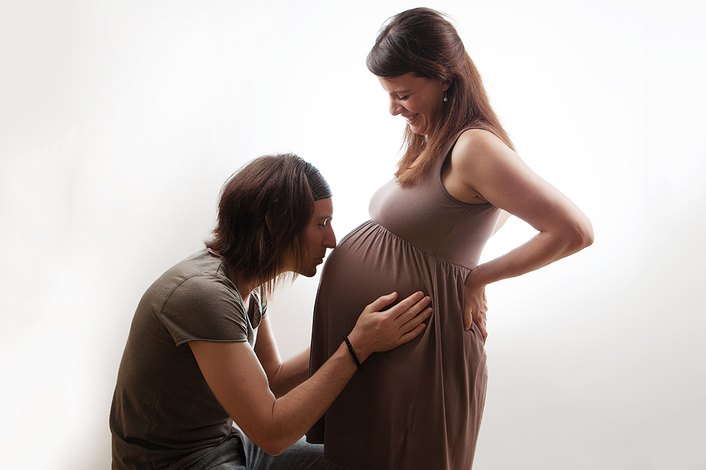 pregnant woman with male partner kissing the tummy