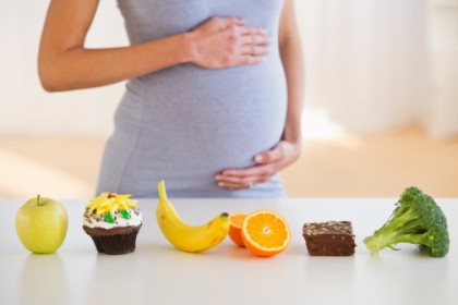 pregnant woman caressing her tummy while watching nutrients on the kitchen table
