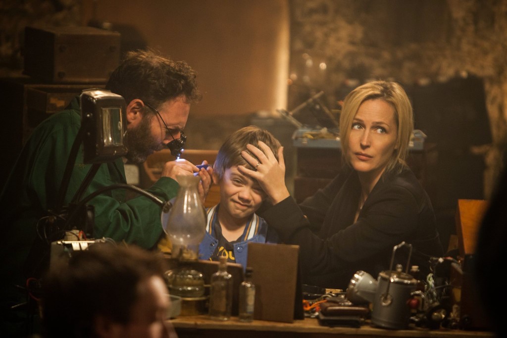 Donald (David McSavage) performs a delicate procedure on Connor (Milo Parker), assisted by Kate (GIllian Anderson) in a scene from Robot Overlords. © MEDIATOR 452 LIMITED/BRITISH FILM INSTITUTE 2014
