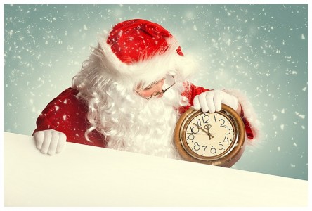 Santa Claus with white blank banner holding a clock showing several minutes to midnight