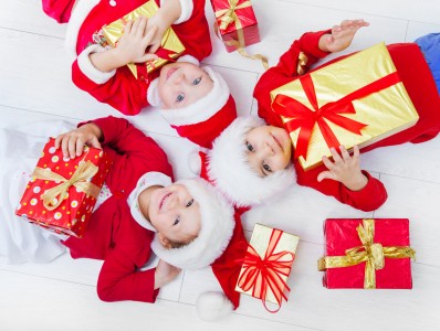 Group of three children in Christmas hat with presents on floor