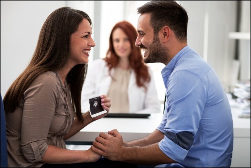 couple with doctor announcing pregnancy