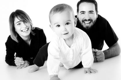 parents smiling at baby crawling