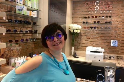 London Mums magazine editor Monica Costa wearing turquoise top posing with blue prescription glasses
