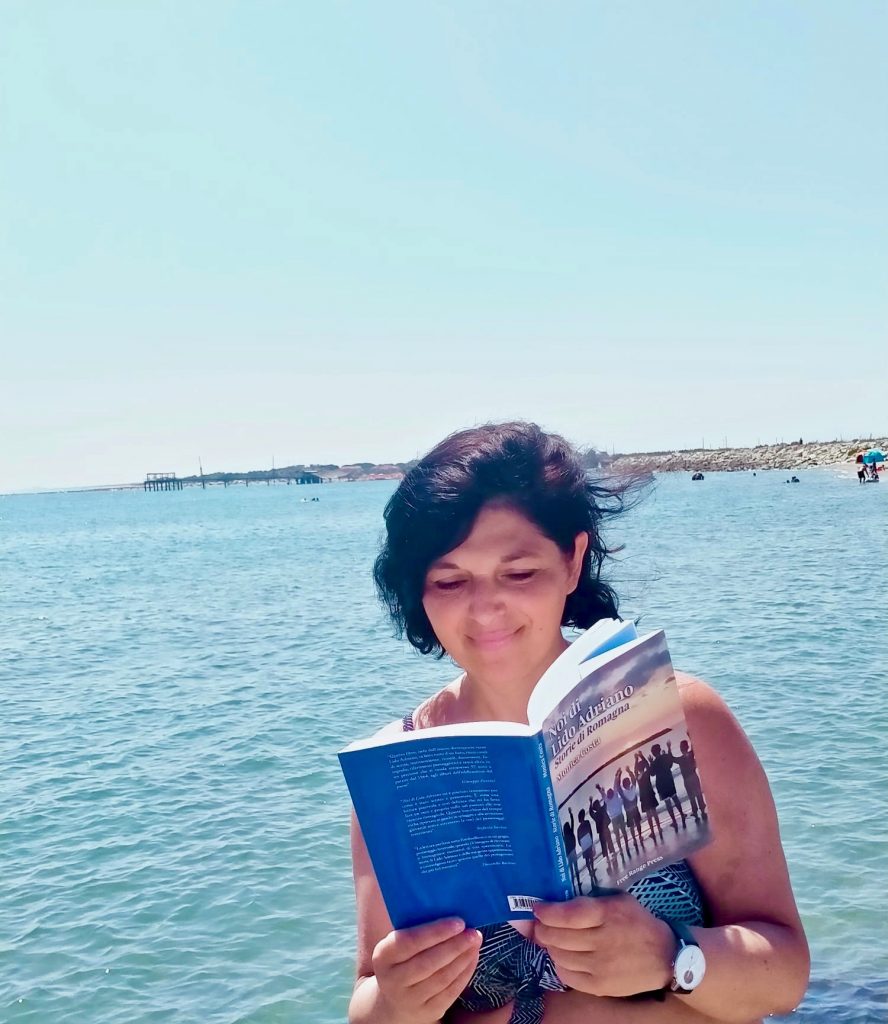 Monica Costa reading her book Noi di Lido Adriano on the beach in Italy 