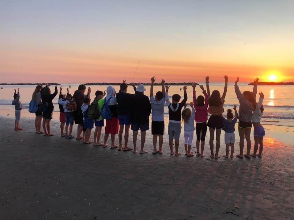 children saluting the sun at Lido Adriano beach in Italy at dawn 