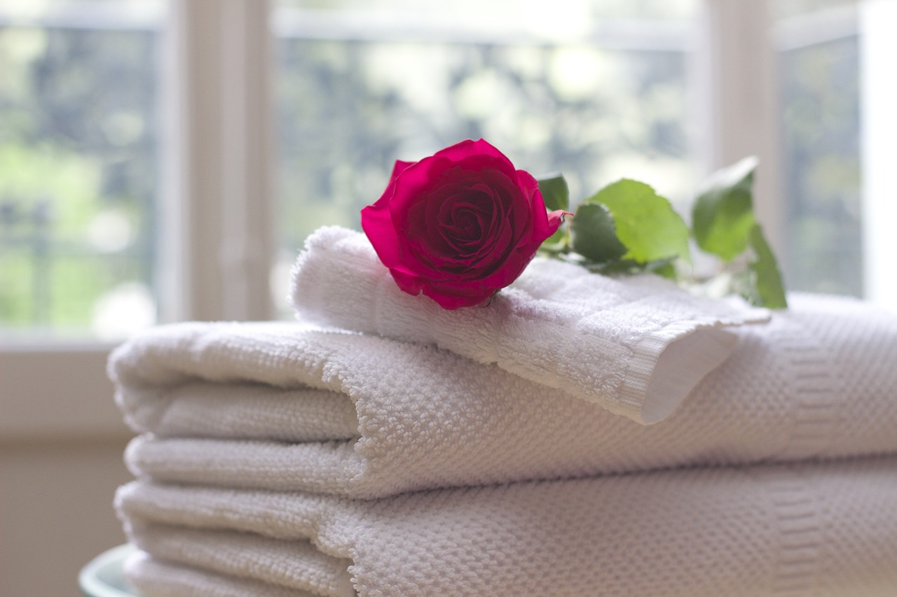 a red rose laying on white towels 