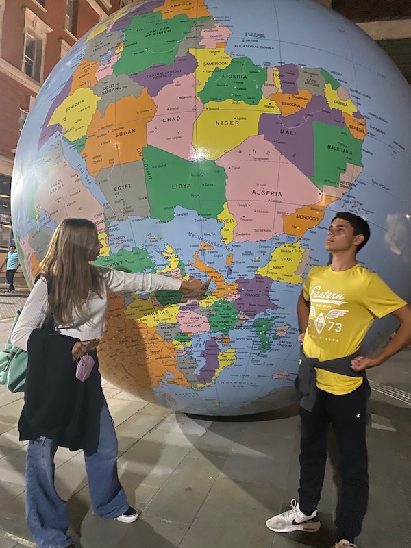 teenage boy and girl standing in front of big globe outside peacock theatre posing for mums magazine