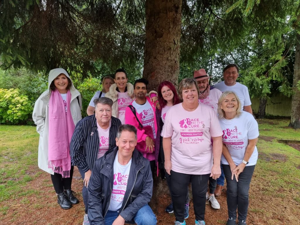 group of people wearing pink shirts and scarves posing for mums magazine