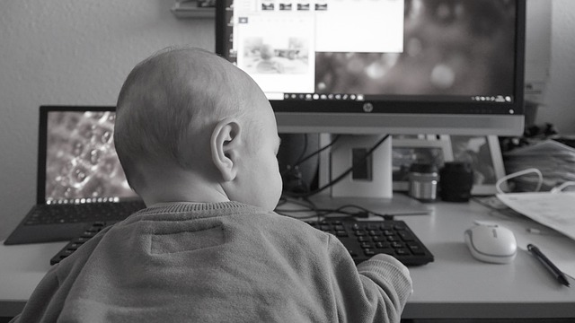 baby sitting in front of a computer in home office posing for mums magazine