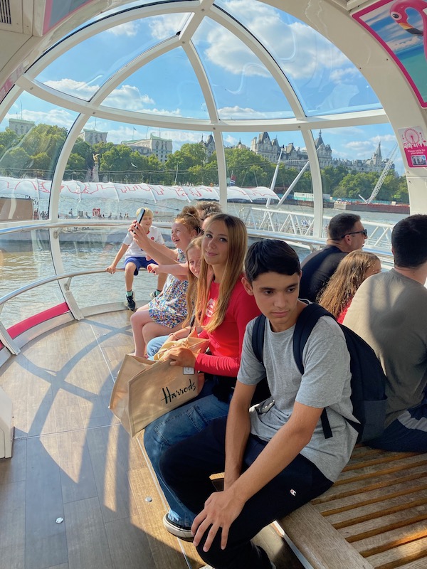Teenage boy and girl sitting in a capsule of the London Eye posing for mums magazine