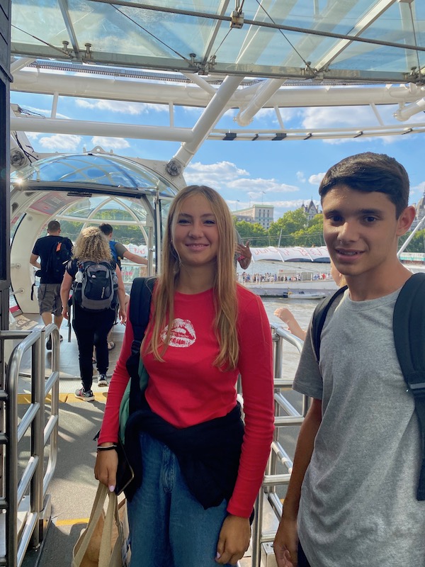 Teenage girl and boy boarding a capsule of the London Eye posing for mums magazine