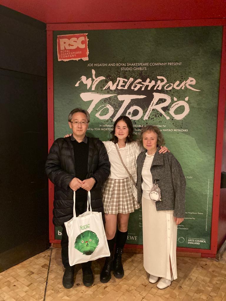 family posing for mums magazine in front of Totoro poster for Barbican theatre show