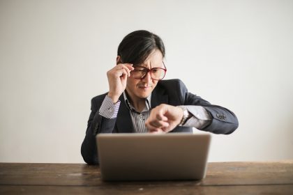 father checking his watch and messages in front of a computer posing for mums magazine