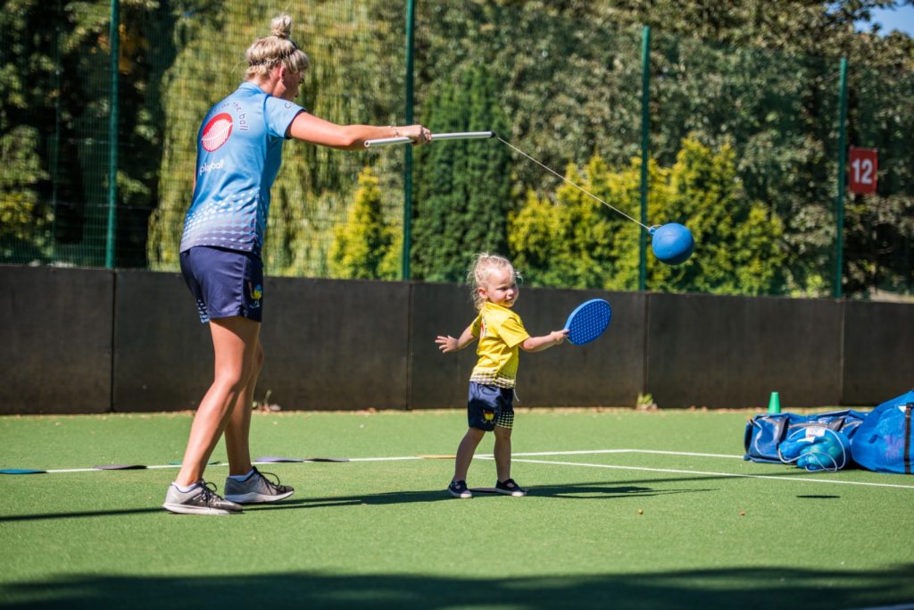 toddler girl wearing a yellow shirt plays with sport teacher posing for mums magazine