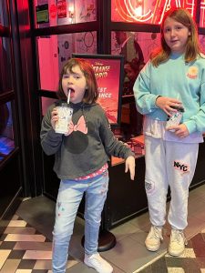 two girls posing for mums magazine at the cinema while drinking
