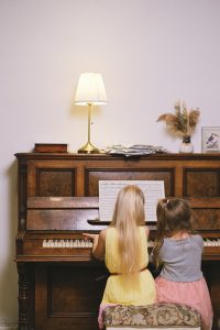 two young girls sitting at a piano