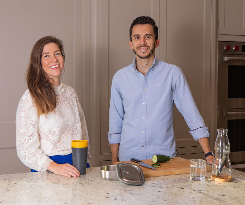 Couple husband and wife founders of the eco swap club posing in their kitchen for mums magazine