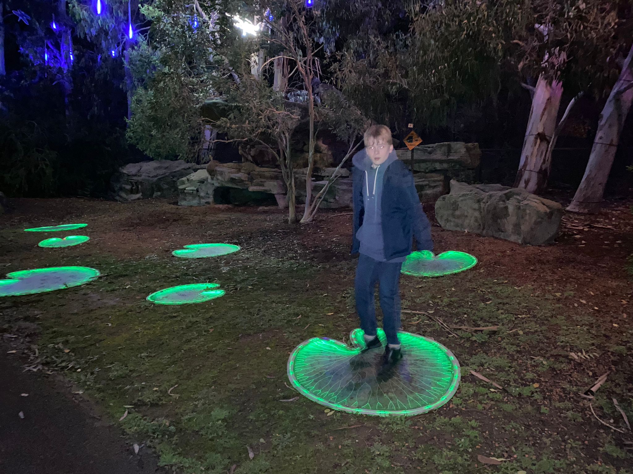 Teenage boy jumps on illuminated lily pads at the Wetland Centre in Barnes posing for mums magazine 