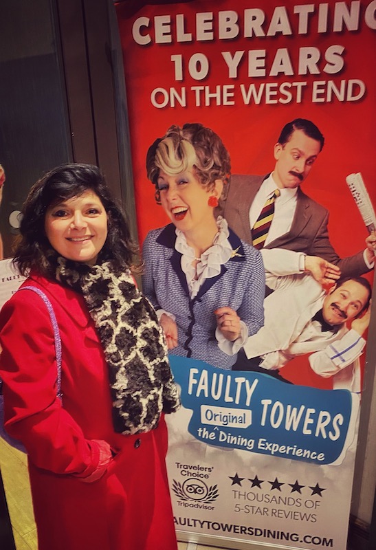 monica costa wearing a red coat at West end for review of The Faulty Towers Dining experience