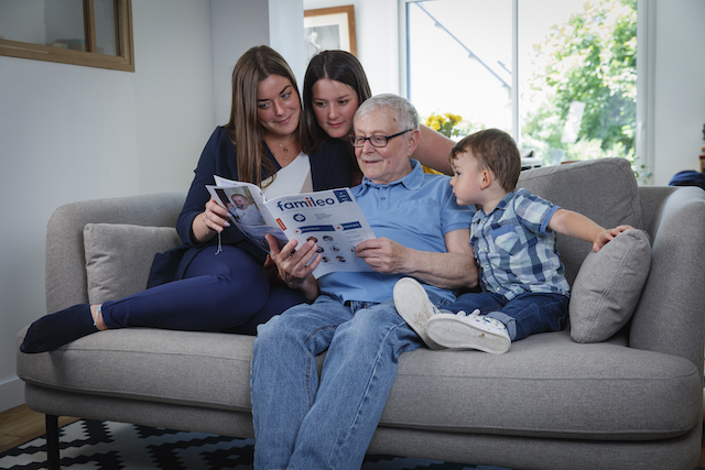 family sitting on the sofa with granfather to check the Family app to help grandparents