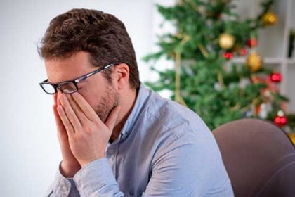 man looking desperate sitting next to the Christmas tree