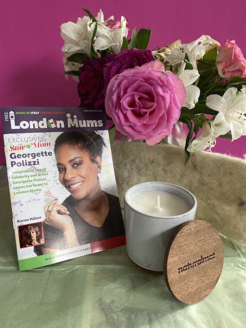 London Mums magazine near a candle and vase of roses and lilies