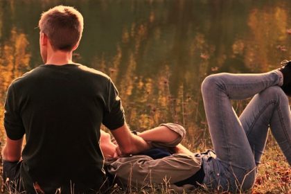 Man and woman lying on the grass near a tree posing for mums' magazine