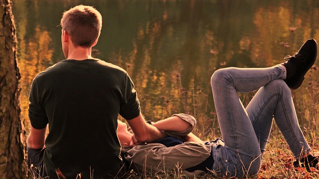 Man and woman lying on the grass near a tree posing for mums' magazine 
