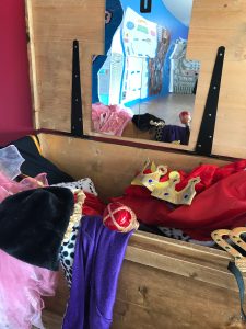 Coronation guest dress up in the Activity Room, with child-height mirror and a stage with the backdrop of Queen Victoria's Coronation ceremony