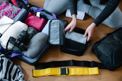 person packing clothes in luggage