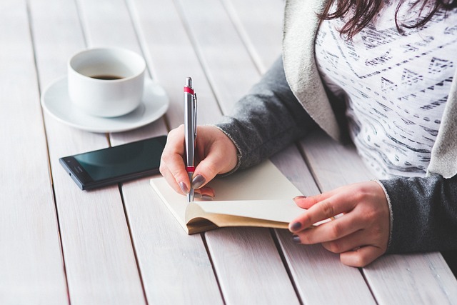 woman writing next to a cup of coffee