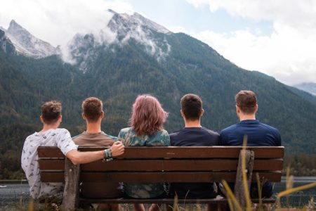 friends sitting on bench in mountains