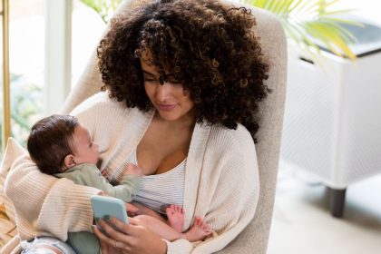 mum holding a baby on the couch while browsing