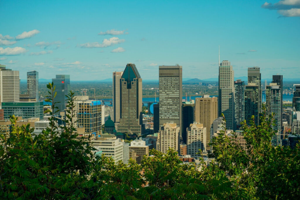 Canada’s cities rarely declare their histories outright. They carry them quietly, embedded in sound, spacing, and routine. Language shifts without announcement. Streets widen or narrow without explanation. What feels cultural at first eventually settles into habit, noticed only when it changes. Moving between Montreal, Quebec City, and Toronto is less about crossing boundaries than adjusting pace. Attention drifts. Behaviour shifts. The cities do not ask to be compared. They ask to be occupied. https://unsplash.com/photos/view-of-a-modern-city-skyline-with-lush-trees-PjyfjC0XnhU?utm_source=unsplash&utm_medium=referral&utm_content=creditShareLink Montreal, Encountered Slowly Montreal does not present a single surface. Streets change character without warning. Conversations overlap. Old stone and newer structures sit close together, neither asserting priority. In Montreal, public life feels close to the street. People linger without planning to. Music appears briefly, then fades. Language moves fluidly through daily routines without being framed as identity. The city feels comfortable with ambiguity. Space That Encourages Pause Sidewalks widen unexpectedly. Parks interrupt neighbourhoods without hierarchy. You stop because stopping fits the space, not because anything has asked you to. These pauses feel unremarkable. They repeat often enough that they stop feeling intentional. Culture here blends into routine, visible only when you slow down enough to notice it. Nothing feels staged. Eastward Without Leaving the Tone Behind Leaving the city does not feel decisive. The Montreal to Quebec train carries the same atmosphere forward, smoothing distance rather than breaking it. Outside, density softens. Inside, conversation stays low. Arrival does not announce a new beginning. The transition feels absorbed rather than marked. Quebec City and Defined Edges Quebec City feels held together more tightly. Streets gather. Buildings cluster. Movement feels guided without being directed. In Quebec City, public space does not sprawl. It frames. You notice how often routes fold back on themselves, how elevation changes alter pace. The city feels deliberate, but not rigid. Language as Background Texture Here, language is not highlighted. It fills space naturally — on signs, in passing conversation, in the cadence of daily exchange. You don’t need to follow every word to sense orientation. Tone carries meaning. Silence carries its own rhythm. Understanding arrives indirectly. Distance That Alters Posture The shift westward happens gradually. Space opens. Streets widen. Movement becomes more linear. Taking the Toronto to Montreal trains feels like easing into a different civic rhythm rather than crossing a cultural line. You adjust posture before you adjust expectation. Speed increases subtly. Structure becomes more visible. Toronto and Continuous Motion In Toronto, the city rarely pauses. Streets extend. Neighbourhoods unfold outward. Movement feels directional. Public space supports flow more than gathering. You pass through rather than linger. Culture appears in designated moments rather than overlapping with routine. The city feels confident in motion. https://unsplash.com/photos/aerial-photography-of-toronto-canada-lZbRV_a4Yxg?utm_source=unsplash&utm_medium=referral&utm_content=creditShareLink Organisation Without Intimacy Toronto’s cultural centres feel clear and defined. You know where to go. You know what will happen there. Participation feels intentional. This clarity creates efficiency. It also creates distance. You enter spaces prepared, then leave them just as deliberately. Culture feels contained rather than diffuse. Similar Functions, Different Temperatures Despite their differences, these cities perform similar work. They gather people. They host exchange. They organise daily movement. What shifts is temperature. Some spaces invite pause. Others prioritise flow. Neither approach dominates. Both persist. The contrast lives quietly in habit. Learning Without Being Told Understanding these cities does not come from explanation. It comes from repetition. Walking the same route twice. Hearing the same street at different hours. Noticing where people stop and where they don’t. The cities teach through use. No one instructs you. Urban Memory That Accumulates Slowly Over time, impressions layer. Stone versus glass. Narrow routes versus open grids. Overlap versus separation. These differences are not symbolic. They are functional, shaped by long use rather than intention. History remains present because it continues to operate. What Lingers Without Resolution Later, what stays with you is not a list of distinctions. It is a shift in awareness — how language altered atmosphere, how space shaped behaviour, how movement adjusted without instruction. Canada’s urban legacies do not compete. They coexist, shaping cities that feel distinct without needing to define themselves against one another. The contrast remains gentle, experienced not as division, but as variation that continues quietly, whether or not you are paying attention.