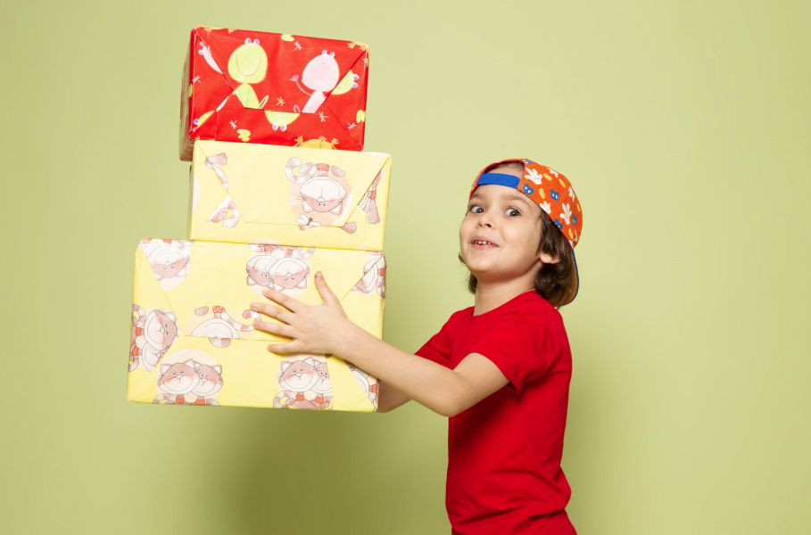 child wearing red shirt and red cap holding presents while posing for a mums magazine